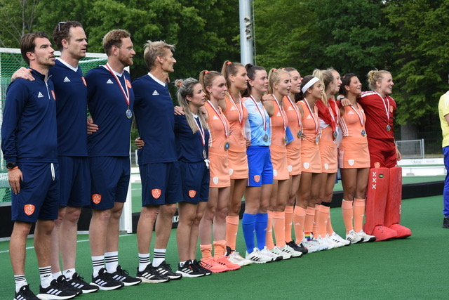 Team en staf met medailles opgesteld langs het veld