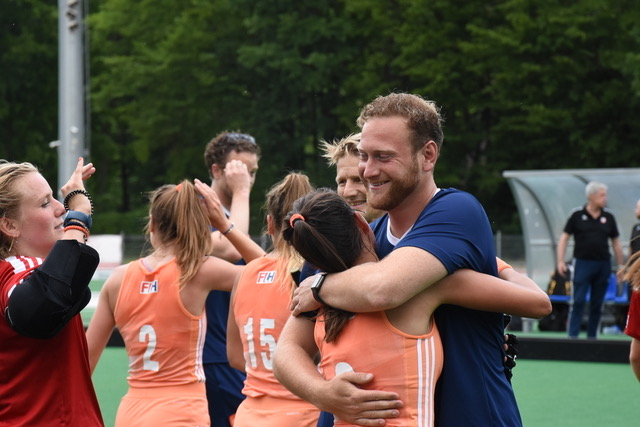 Sporters en staf vieren samen een overwinning op het veld
